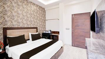 A modern hotel room with a large bed, a flat-screen TV mounted on the wall, and a wooden door.