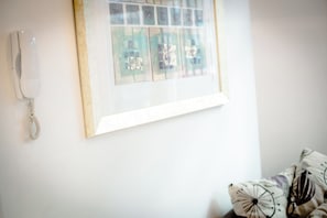 A white wall with a framed window, a white telephone, and a patterned cushion. - Cosy King's Road Flat - with off-road Parking (Harrogate)