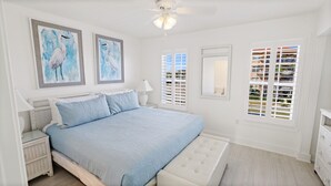 A bedroom with a large bed, two framed wall art pieces, a ceiling fan, and a window with blinds. - 12B - 2BR $700+ in freebies incl golf, On Beach (Miramar Beach)