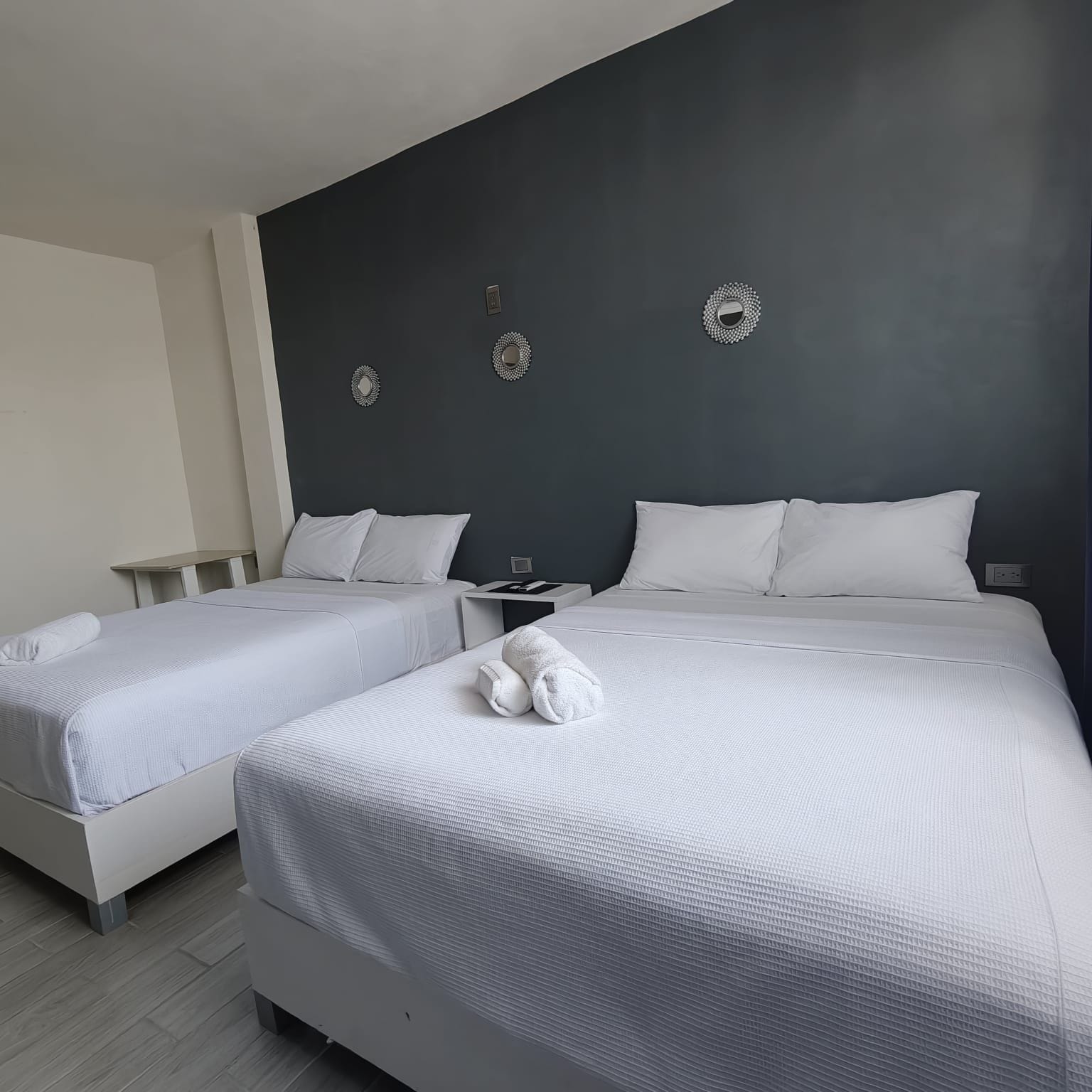 A hotel room with two beds, a bedside table, and decorative wall mirrors.