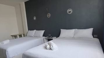 A hotel room with two beds, a bedside table, and decorative wall mirrors.