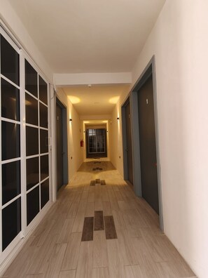 A hallway with a tiled floor, a fire extinguisher, and a door with a number.