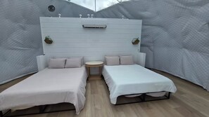A room with two beds, a small round table, and a white headboard with plants. - Luxury Glamping Estate with Hot Tub Near San Jose (Gilroy)