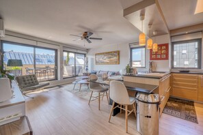 A spacious living area with a dining set, a sofa, a ceiling fan, and a kitchen with a sink and countertop. - Stunning Flat • AC & Parking in Bordeaux (Bordeaux)