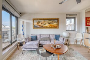 Un salon moderne avec un canapé d’angle, une table basse et un tableau accroché au mur.