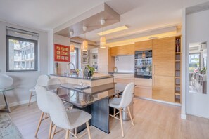 A modern kitchen with a central island, wooden cabinets, and pendant lighting. - Stunning Flat • AC & Parking in Bordeaux (Bordeaux)