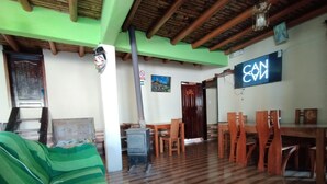 A room with a green sofa, wooden dining table, chairs, a stove, and a wall with a 'CAN' sign.