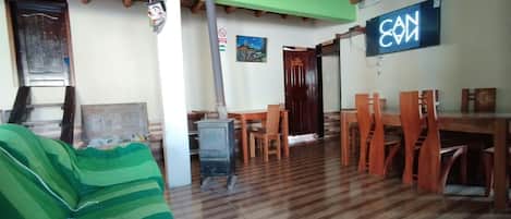 Una habitación con sofá verde, mesa de comedor de madera, sillas, estufa y una pared con un cartel que dice 'CAN'.
