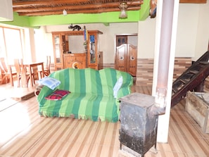 A room with a green-striped sofa, wooden furniture, a staircase, and a tiled floor.