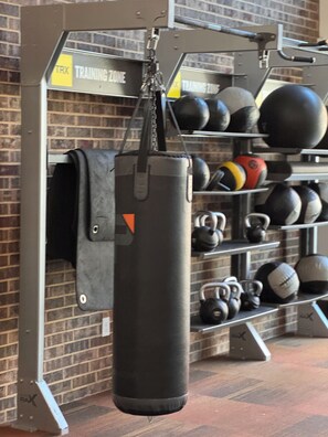 Ein Fitnessraum mit einem Sandsack, Kettlebells und einem Regal voller Gewichte.