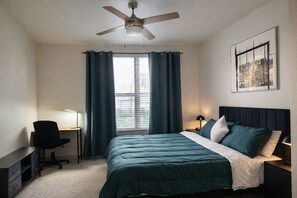 A bedroom with a bed, desk, chair, and a ceiling fan. - Vibrant DT Condo NR Farmers Market (Dallas)