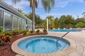 A swimming pool with a tiled edge, surrounded by landscaped greenery and palm trees. - 8 guests /4 beds /3 baths /Lucaya Village (13-108) (Kissimmee)
