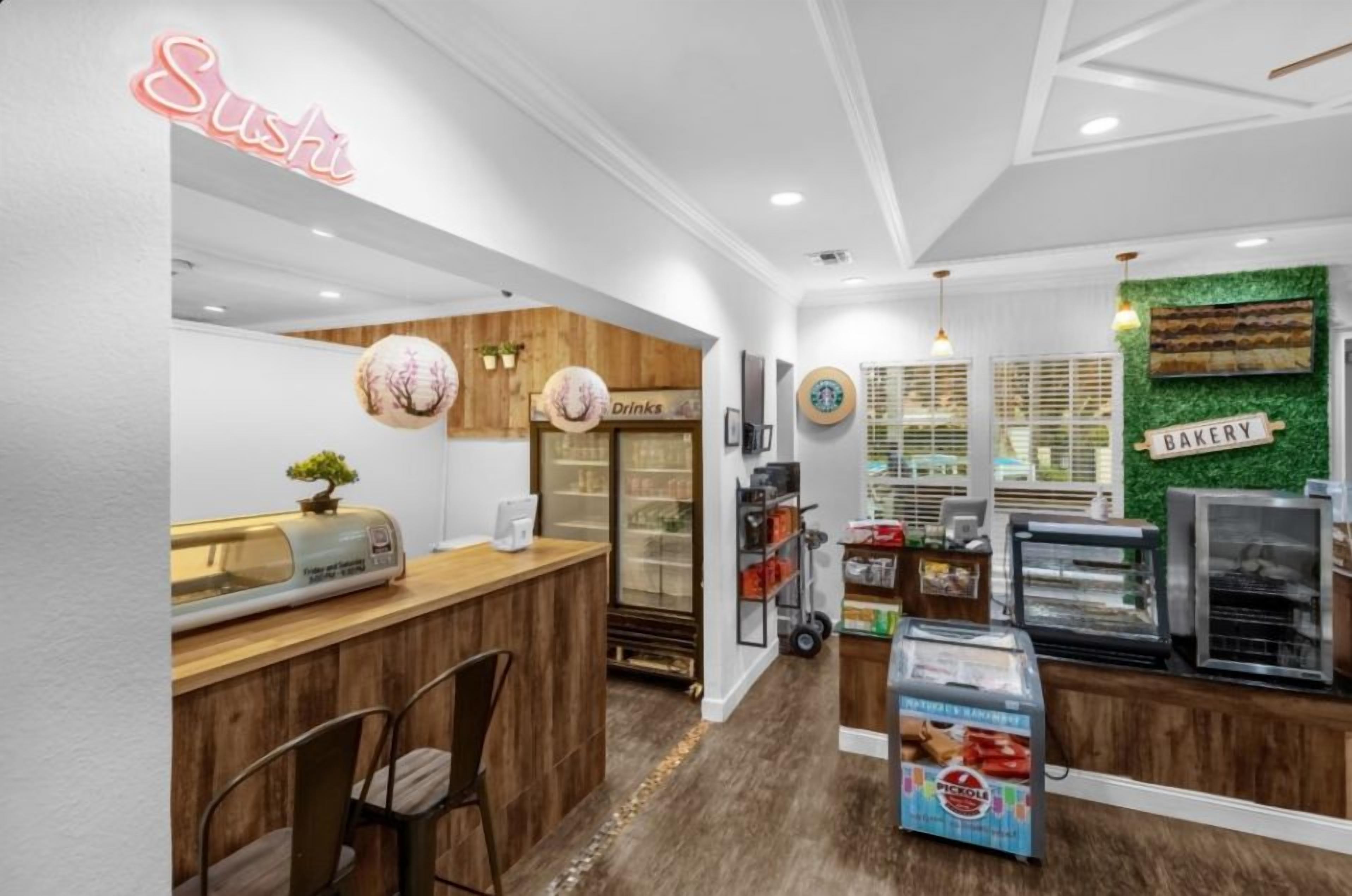 Un bar à sushis avec une enseigne au néon, un espace dédié aux boissons et un coin boulangerie agrémenté d’un mur végétal.