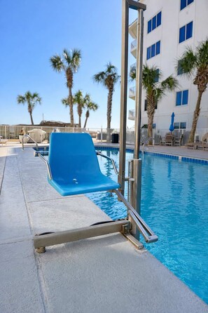 Ein Poolbereich mit blauem Liegestuhl, Pool und Palmen.