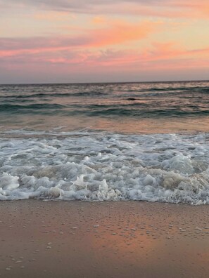 Een strand met golven en een zonsondergang.