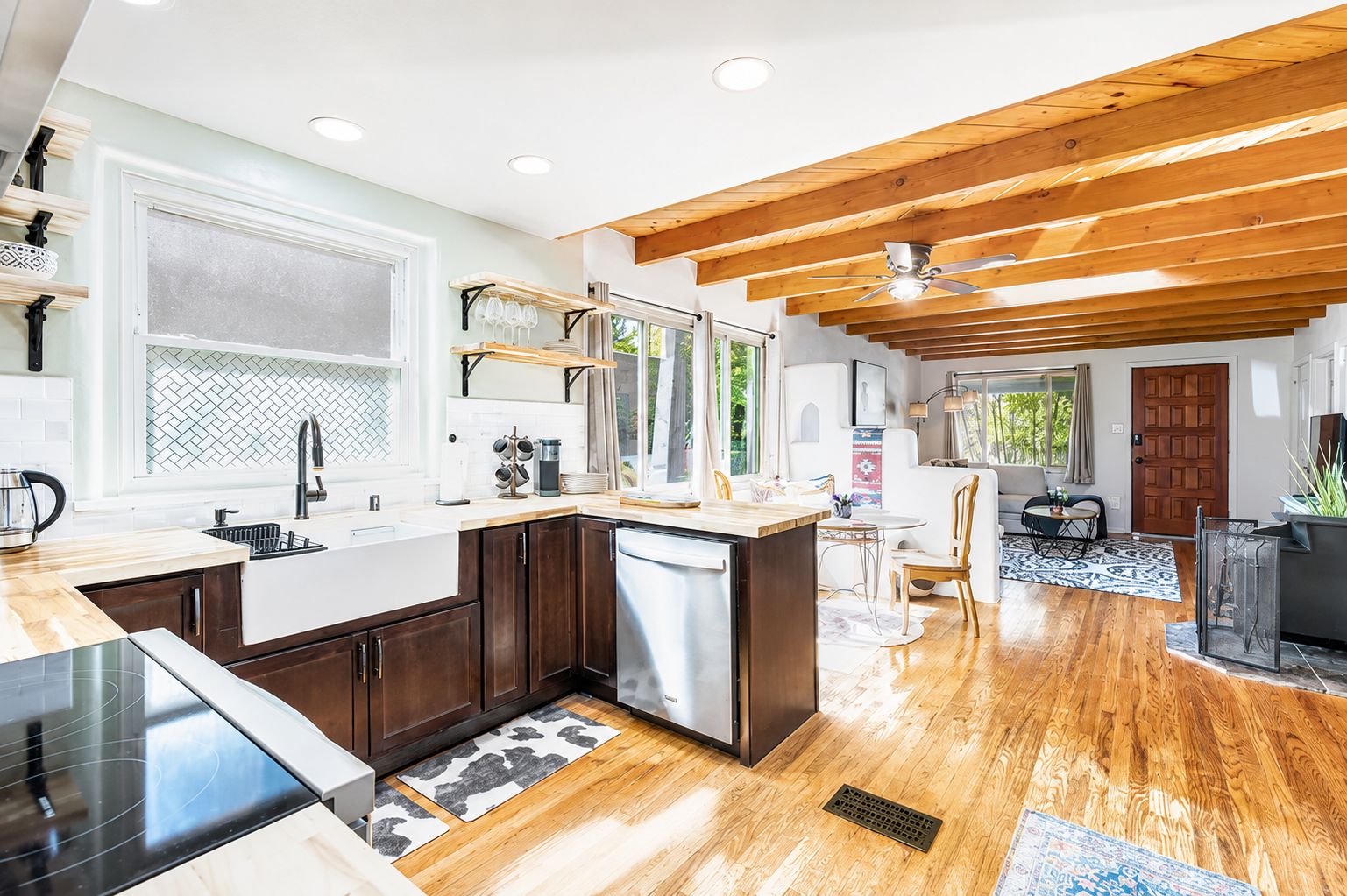 A modern kitchen with a central island, wooden ceiling beams, and a dining area with a view.