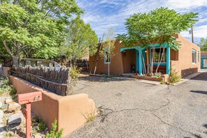 A traditional adobe house with a gravel driveway, a wooden fence, and a mailbox. - Casa de Vaca | Adobe Near Downtown - A/C (Santa Fe)