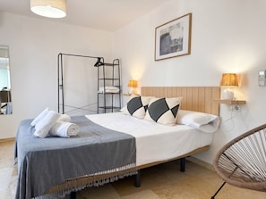 Habitación de hotel ordenada con cama, lámpara de noche, estante en la pared, cuadro enmarcado y una escalera de pie.