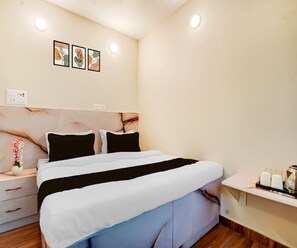 Ein ordentlich bezogenes Bett mit einem schwarz-weiß gestreiften Überwurf, ein Nachttisch mit einer Blumenvase und eine Wand mit drei gerahmten Kunstwerken.