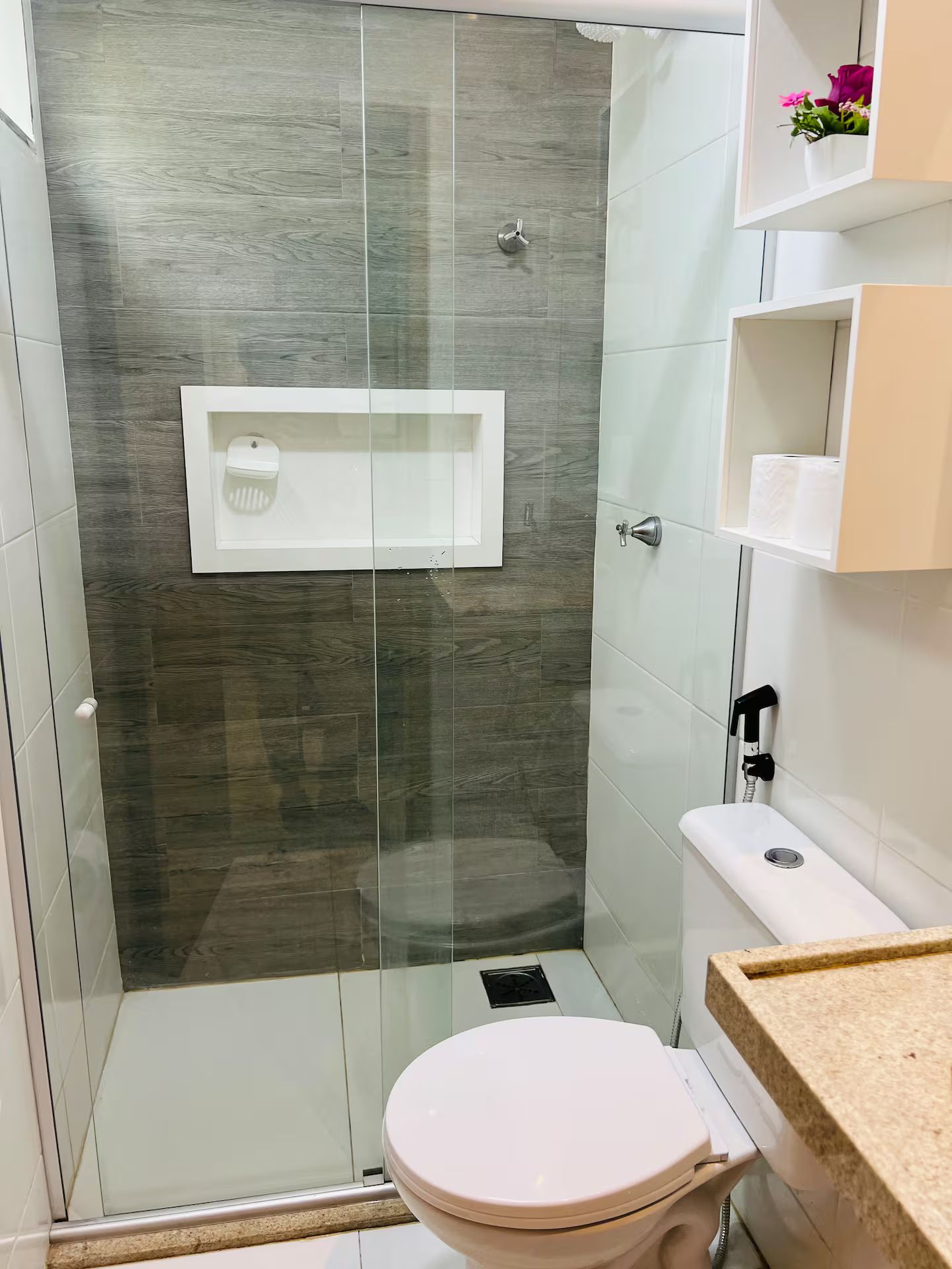 A bathroom with a glass-enclosed shower, a toilet, and a sink with a countertop.