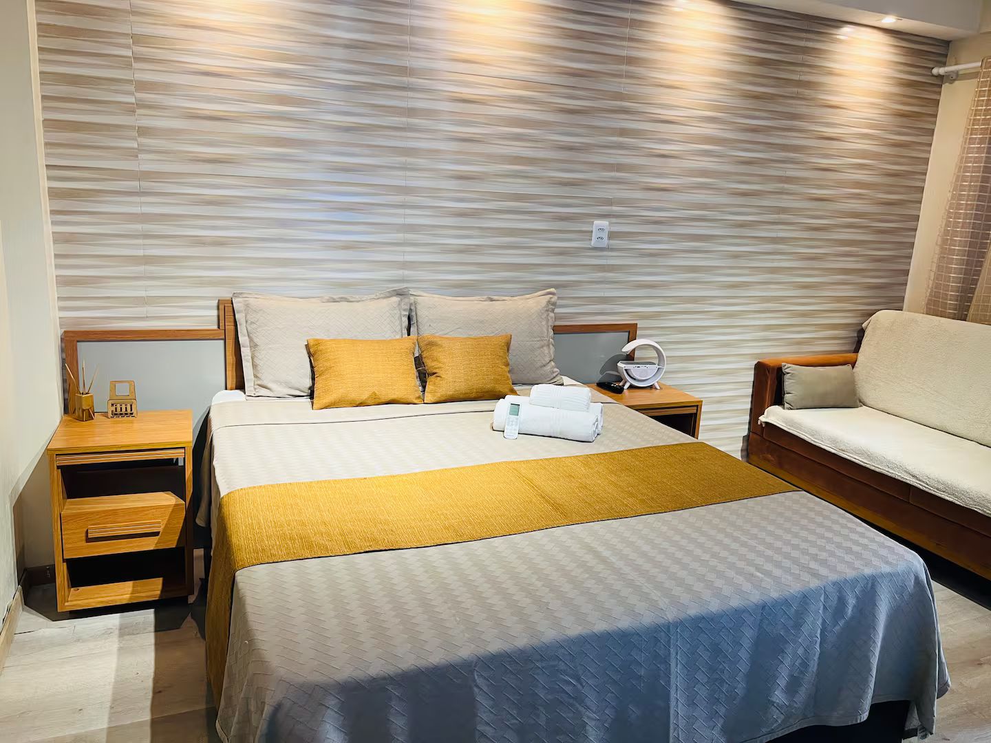 Ein Hotelzimmer mit einem Bett, einem Nachttisch, einer Couch und einer Wand mit einer strukturierten Oberfläche.
