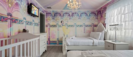 A bedroom with a bed, nightstand, dresser, and a crib.