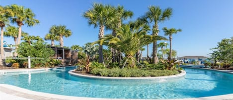 A swimming pool surrounded by palm trees and a wooden deck.
