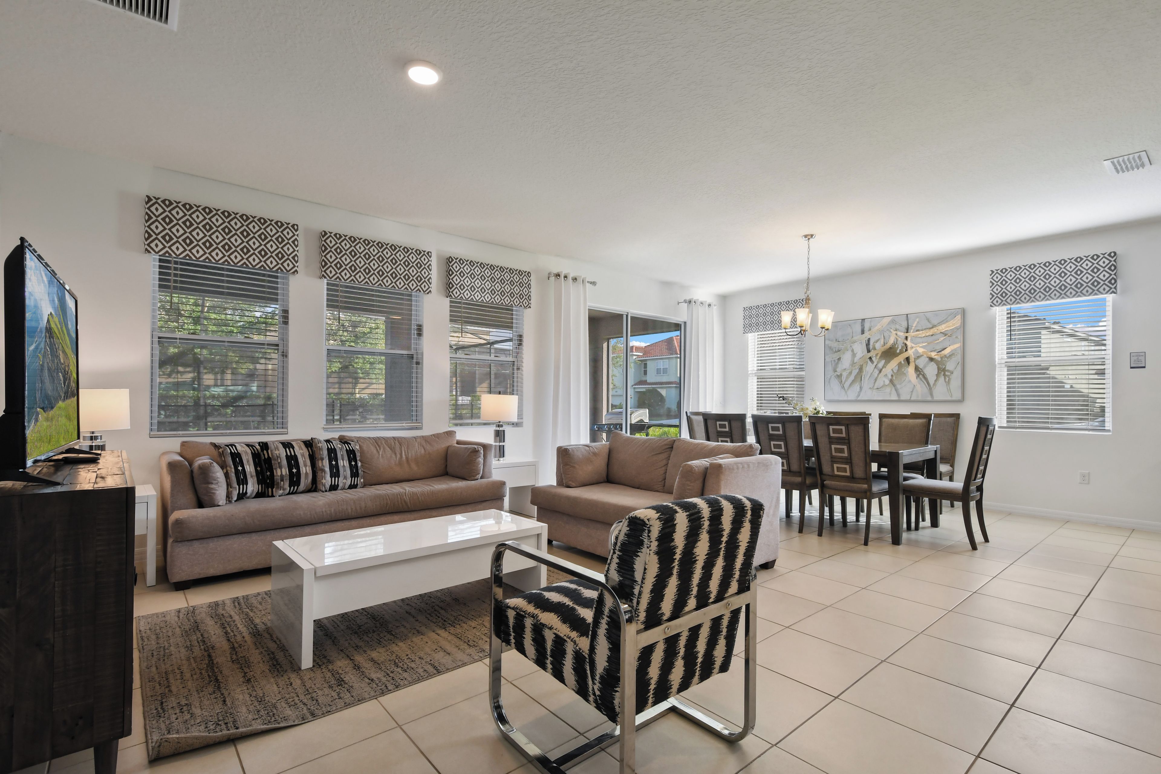 A modern living room with a sofa, armchairs, a coffee table, and a dining area with chairs and a table.