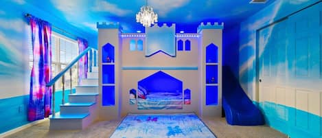 A bedroom with a castle-themed design, including a bed, a chandelier, and a staircase.