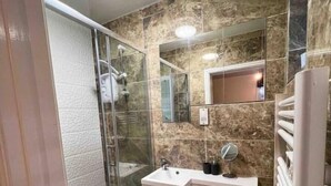 Un bagno con box doccia in vetro, lavandino bianco, specchio e water.