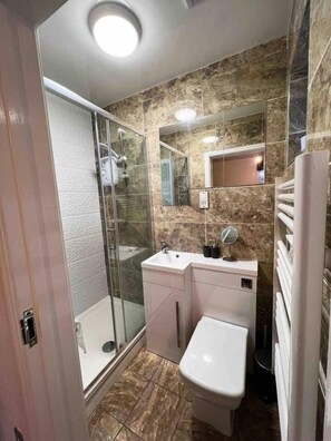A bathroom with a glass shower enclosure, a white sink, a mirror, and a toilet. - Modern 1 Bedroom flat in City center (Leicester)
