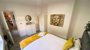 Una camera d'albergo con un letto, una cassettiera, uno specchio e un quadro appeso al muro.