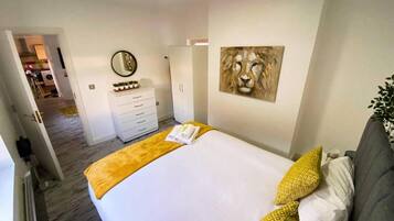 A hotel room with a bed, a dresser, a mirror, and a painting on the wall.