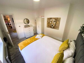A hotel room with a bed, a dresser, a mirror, and a painting on the wall. - Modern 1 Bedroom flat in City center (Leicester)
