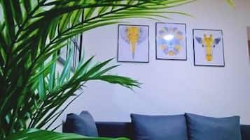 A living room with a dark grey sofa, a coffee table with a glass and remote control, and a large green plant.