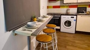 Una cucina compatta con angolo bar, lavatrice e schienale rivestito in piastrelle.