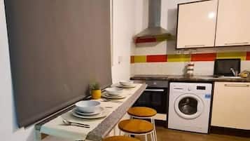 A compact kitchen with a bar area, a washing machine, and a tiled backsplash.
