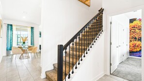 A staircase with a black handrail and stone steps leading to a white door with a colorful floral mural. - 4BR w Screened Pool & Resort Access Near Parks (Kissimmee)