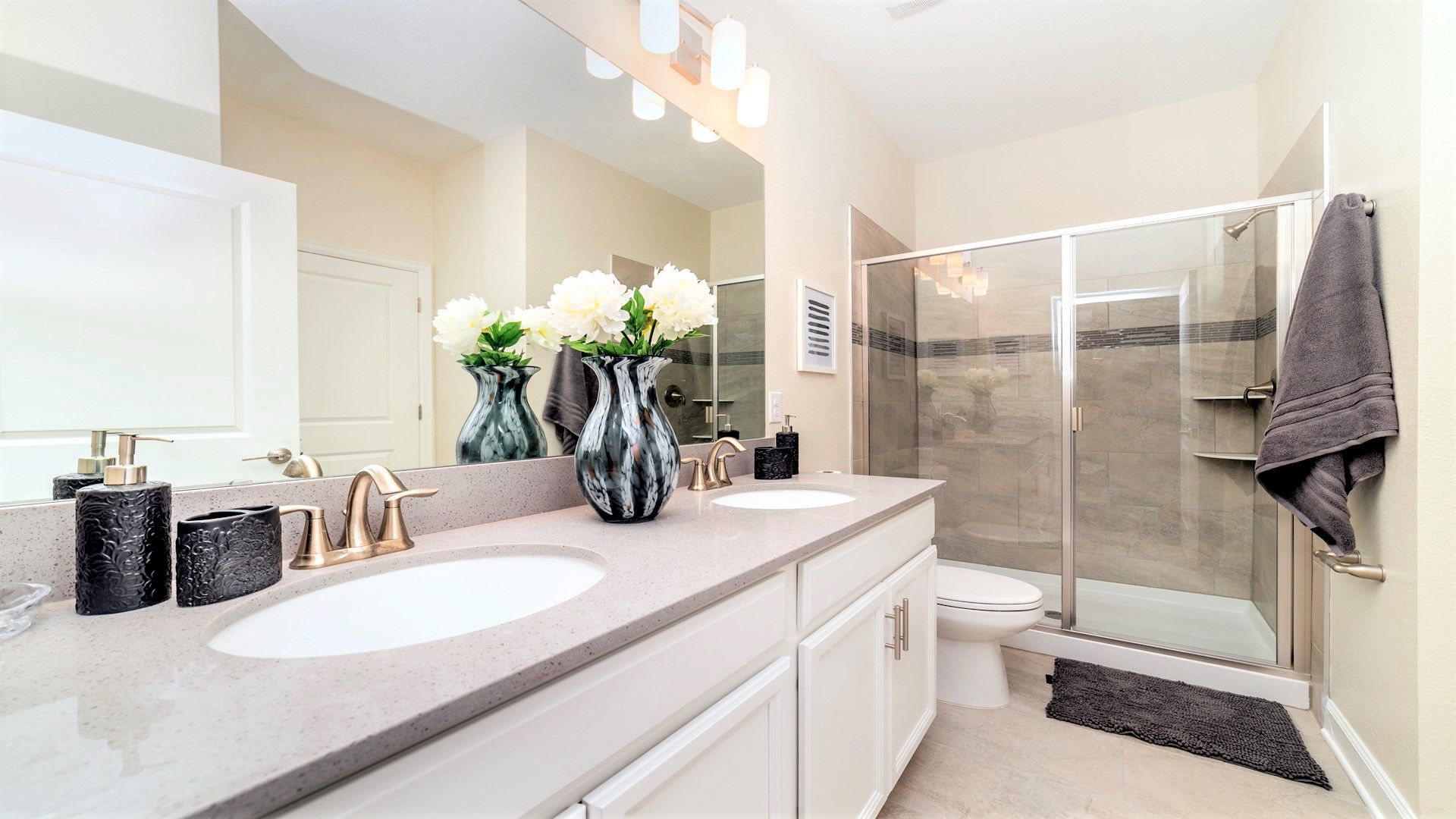 A modern bathroom with two sinks, a glass shower enclosure, and a large mirror.