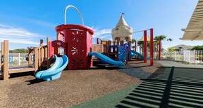 A playground with a red climbing structure, a blue slide, and a castle-like playhouse. - Spider-man Gamer Paradise + Themed Bedrooms (Kissimmee)