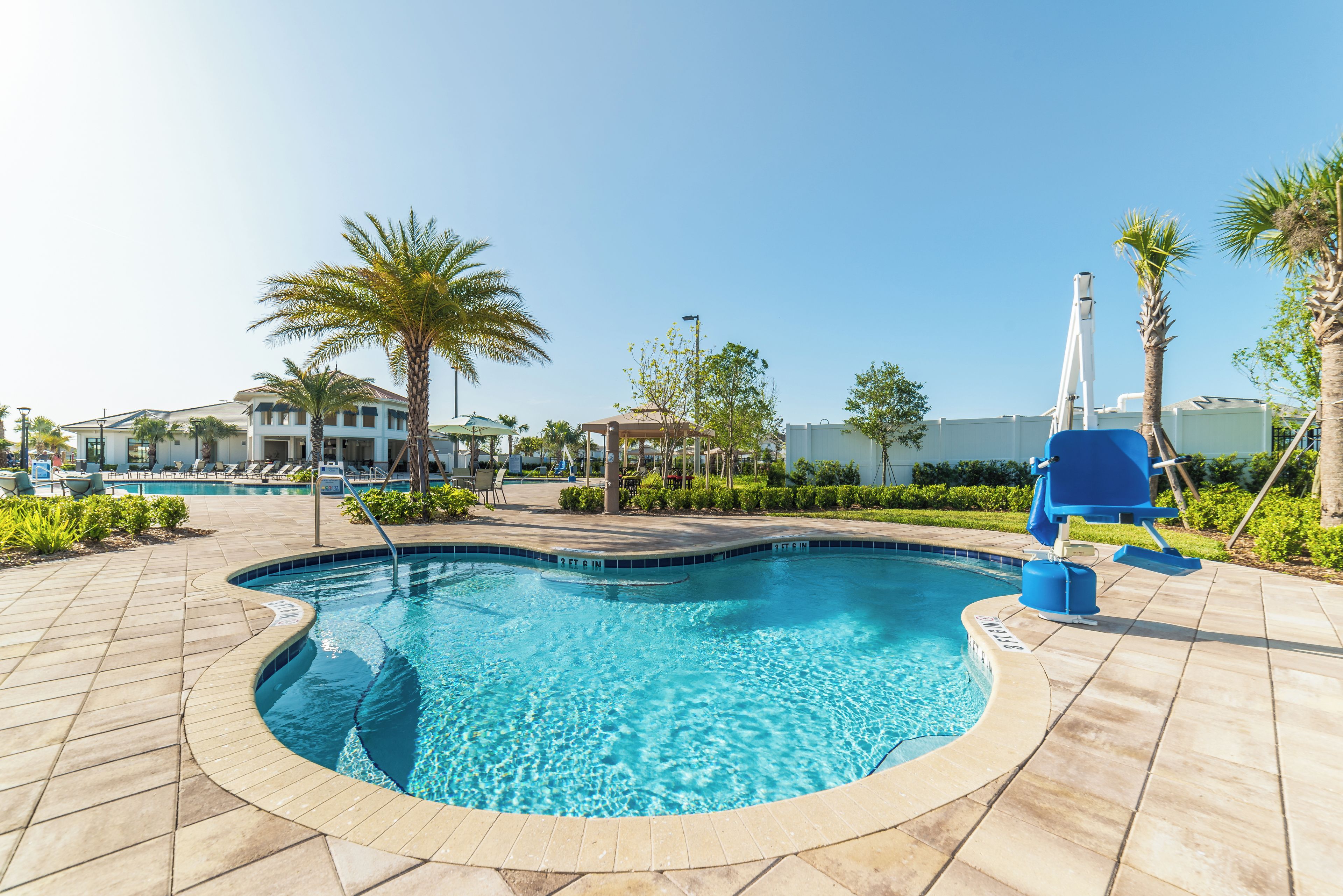 A swimming pool with a 3 ft 6 in depth, surrounded by palm trees and lounge chairs.