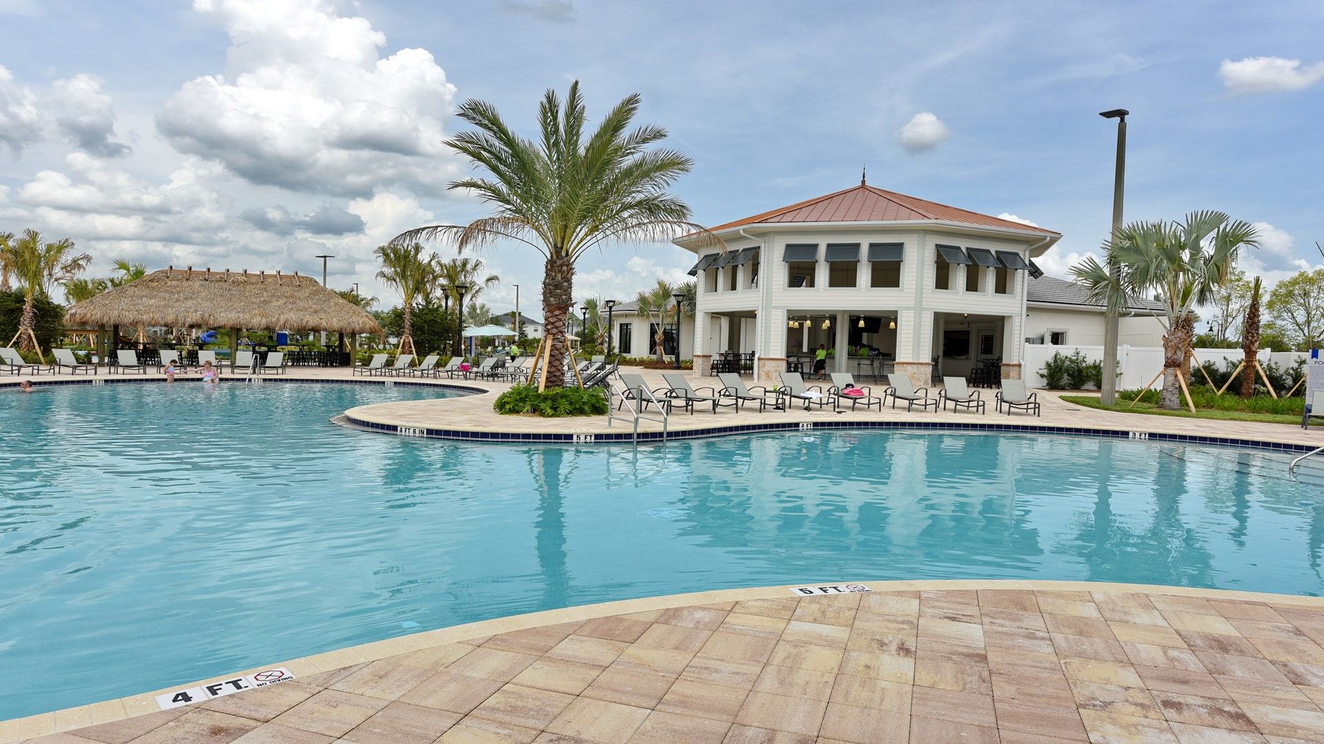 A swimming pool with lounge chairs and a building with a red roof.