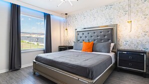 A modern bedroom with a large bed, dark wood flooring, and a window with curtains. - Avenger's Gameroom, Theater, More Themed Rooms! (Kissimmee)