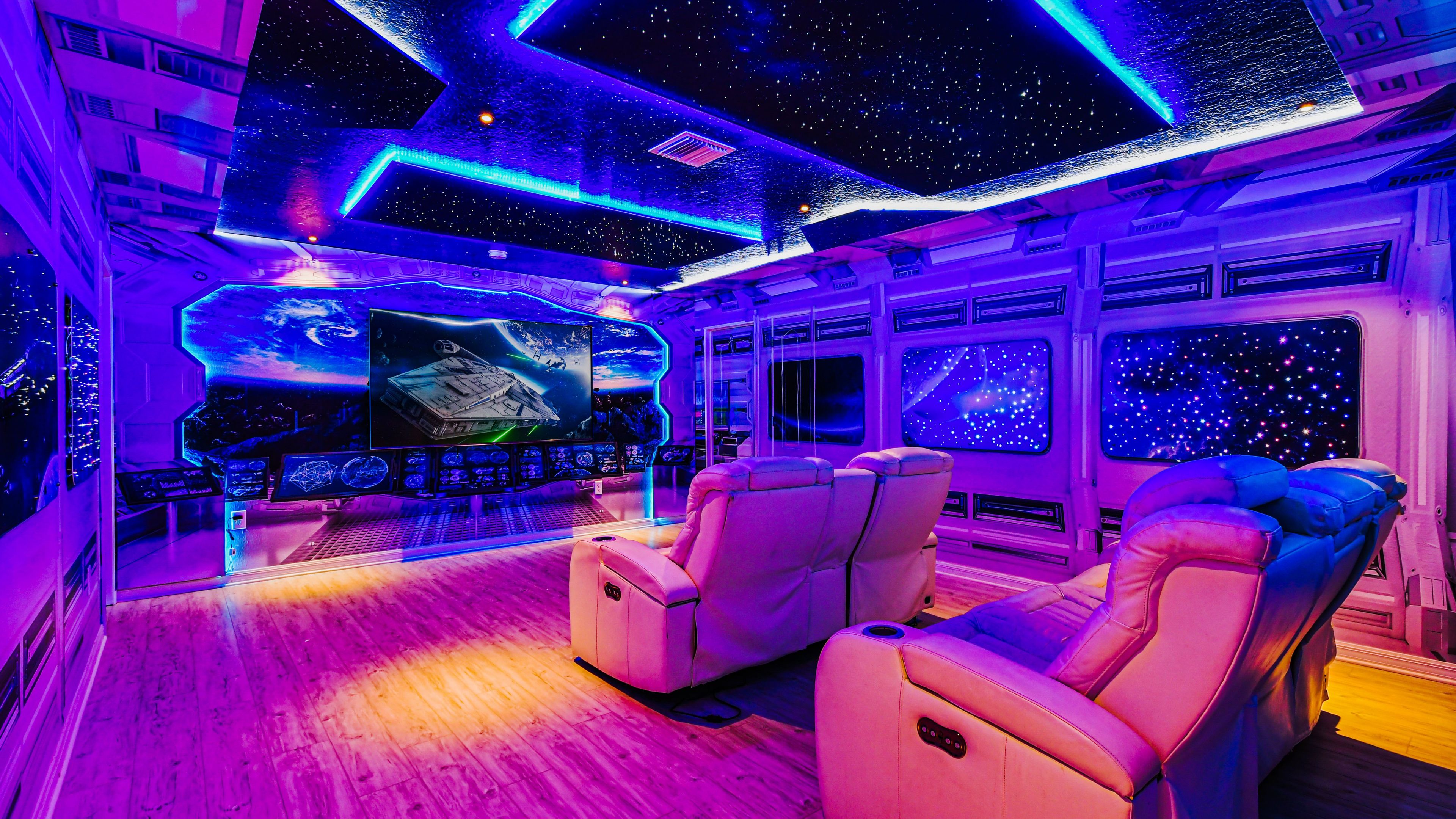 A room with a starry ceiling, a large screen displaying space scenes, and multiple windows with starry views.