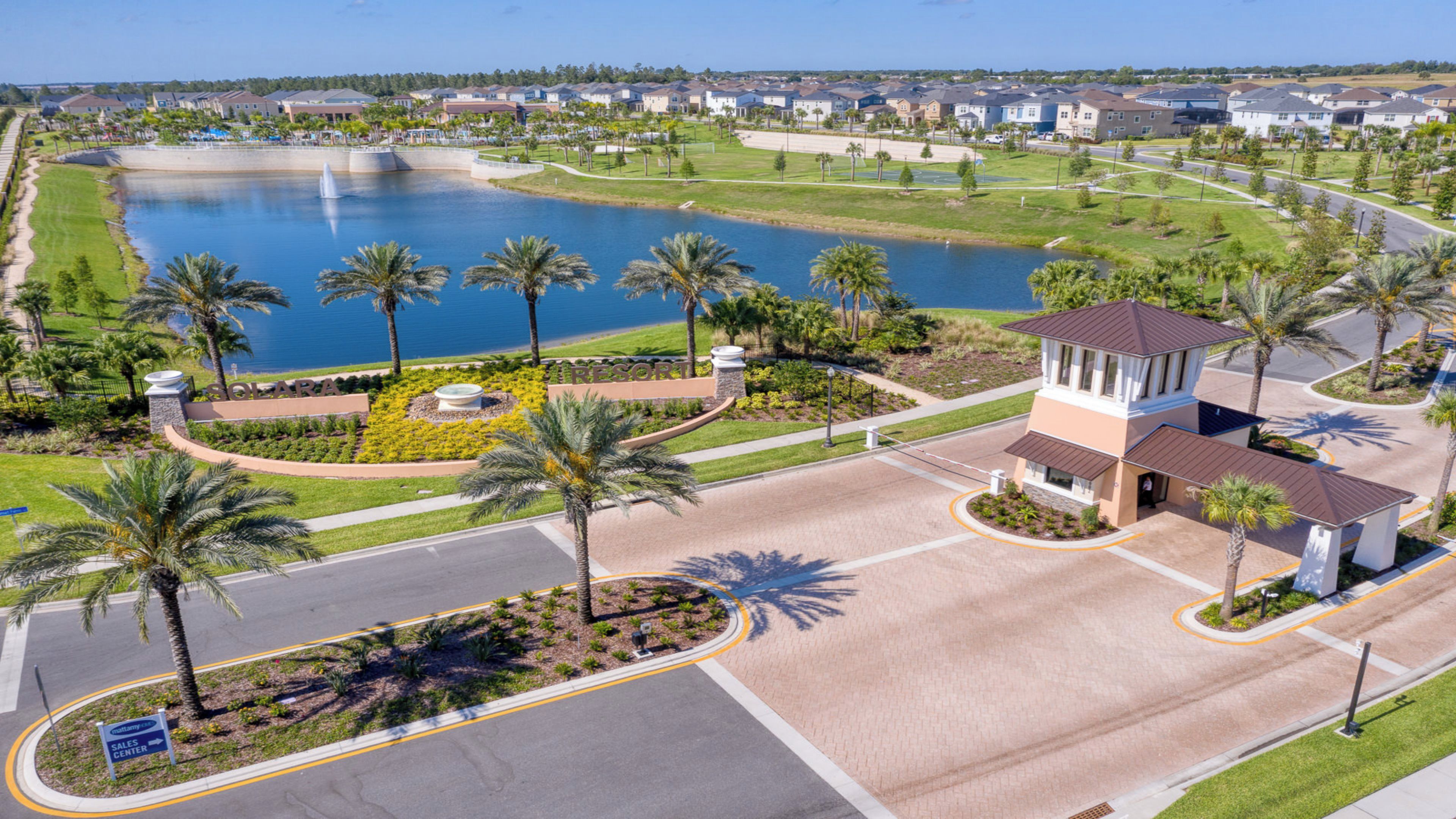 A golf course with a water feature, palm trees, and a building with a tower.