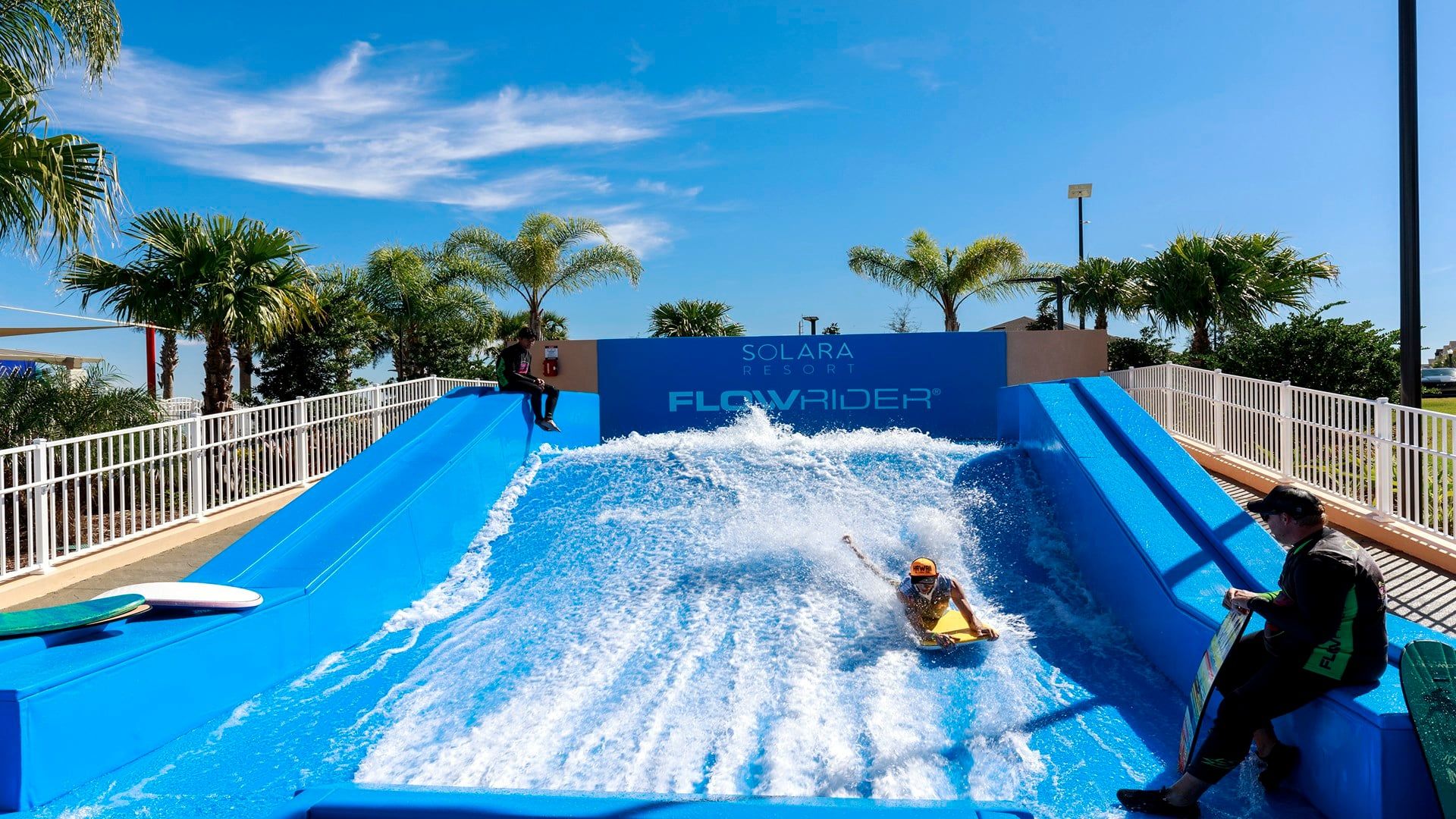 Een glijbaan bij Solara Resort, met een helderblauwe lucht en palmbomen op de achtergrond.
