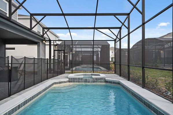 Una piscina con hidromasaje, rodeada por una zona cubierta con estructura de metal y paredes de malla.