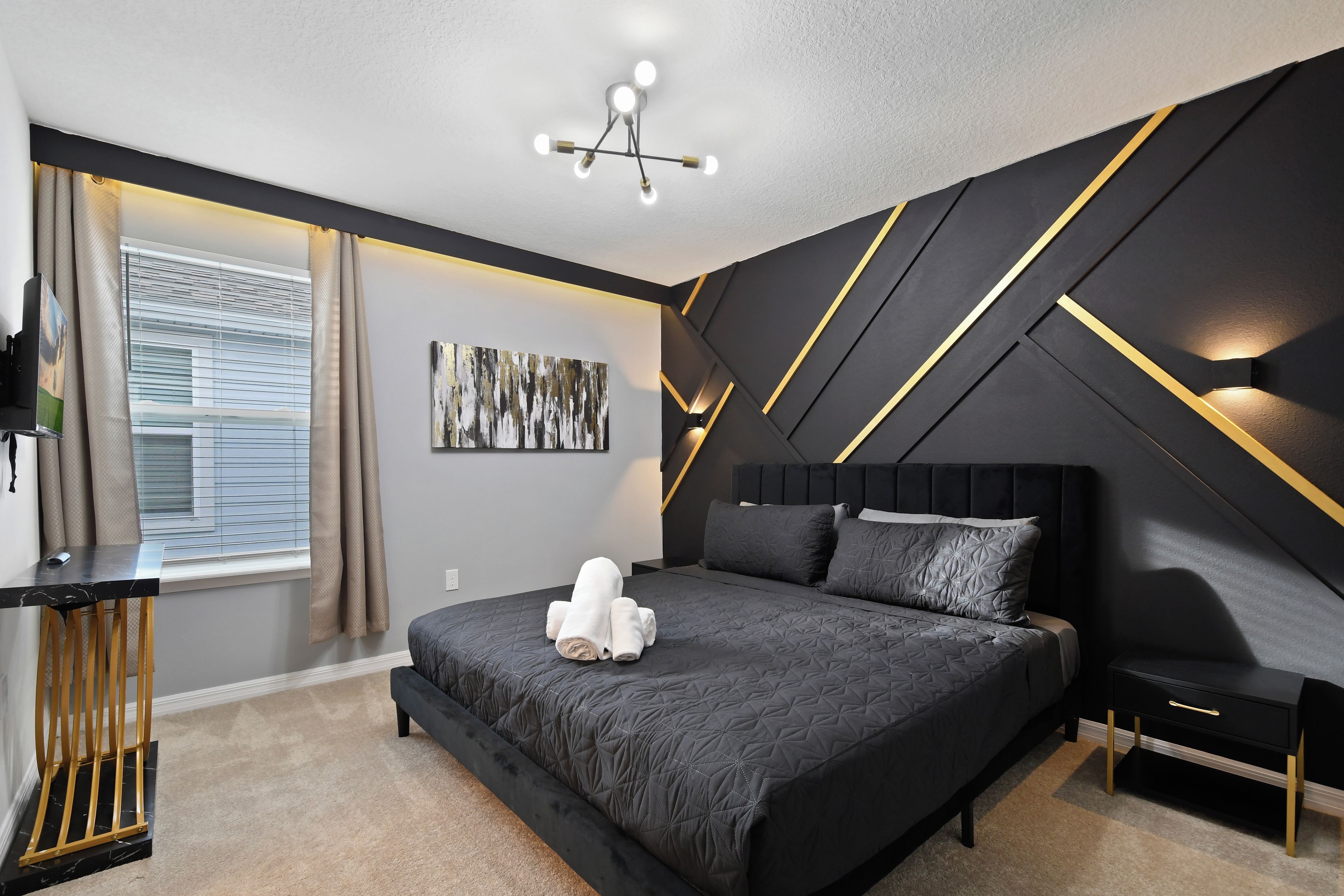 A modern bedroom with a bed, a desk, and a window with blinds.