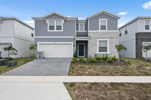 A two-story residential building with a garage, a stone accent wall, and a well-maintained front yard. - Luxury Villa w/ Pool, Spa & Star Wars Theater (Davenport)