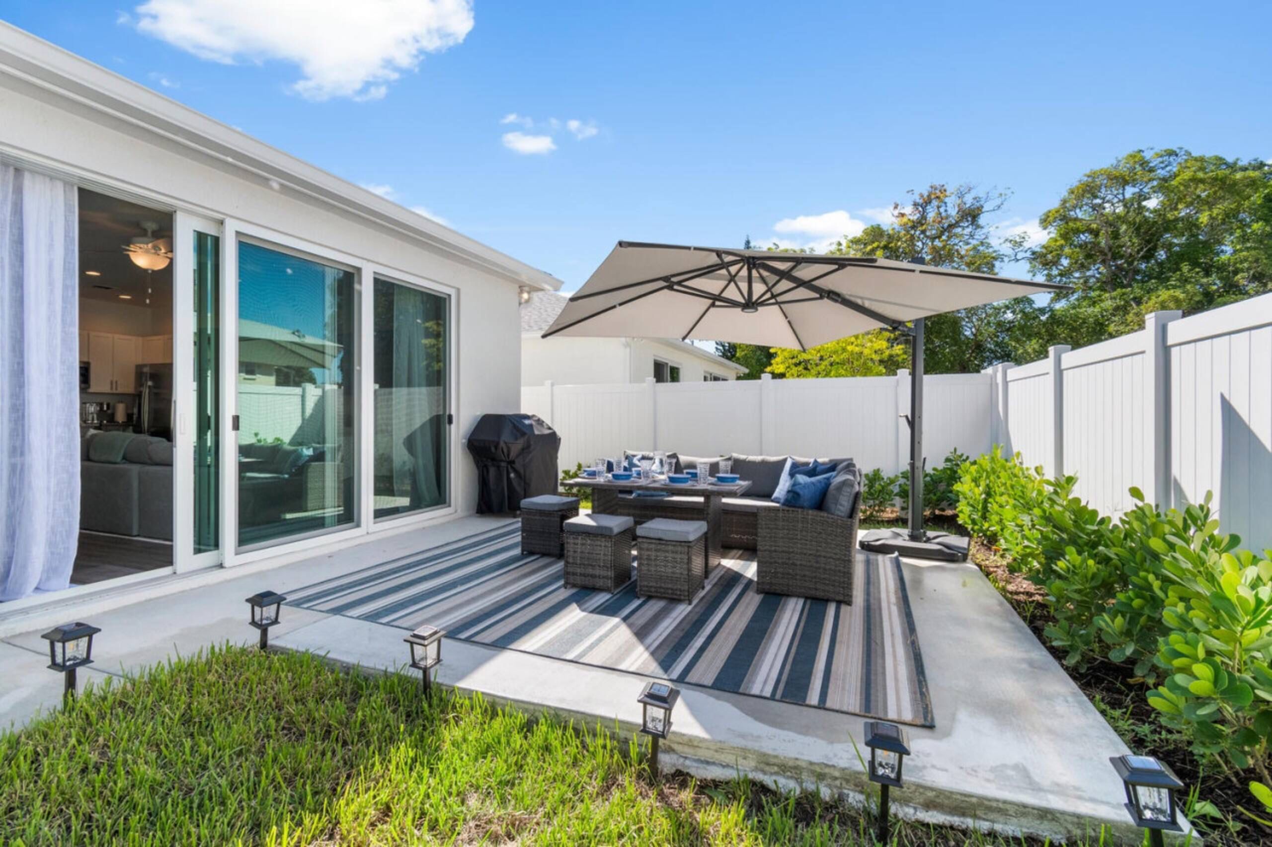 A backyard with a patio area, outdoor furniture, and a grill.